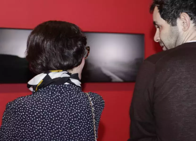Algunos de los visitantes a la inauguración «Peso y levedad» comentan las fotografías expuestas.