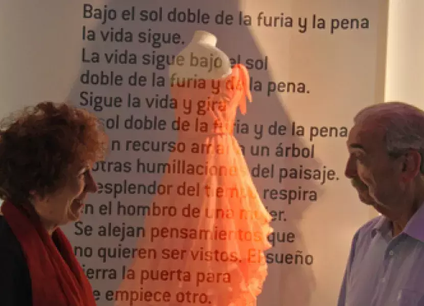 El escritor Juan Gelman y su esposa Mara de La Madrid frente al traje y al texto del poema.