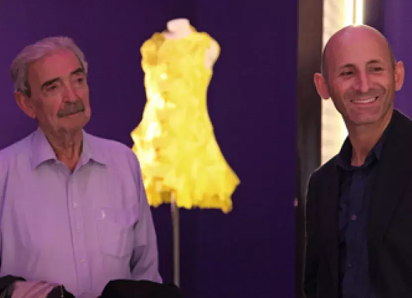 El escritor Juan Gelman y Modesto Lomba, Presidente de la Asociación de Creadores de Moda de España. Al fondo, el vestido de Modesto Lomba inspirado en el texto de Gabriel García Márquez «100 años de soledad»