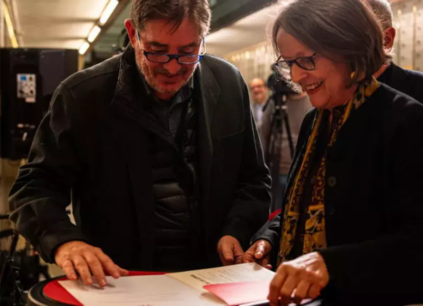 El director del Instituto Cervantes muestra a Elena García de Paredes de Falla el documento que debe firmar.