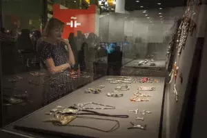 Una visitante a la exposición observando joyas