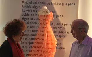 El escritor Juan Gelman y su esposa Mara de La Madrid frente al traje y al texto del poema.