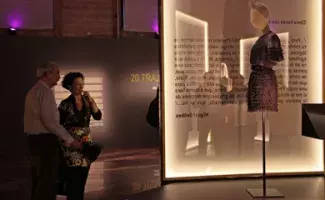 El escritor y la comisaria de la exposición observan el traje de la diseñadora Carmen March.